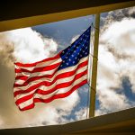 Dramatic view of the American flag waving on a bright day with clouds.